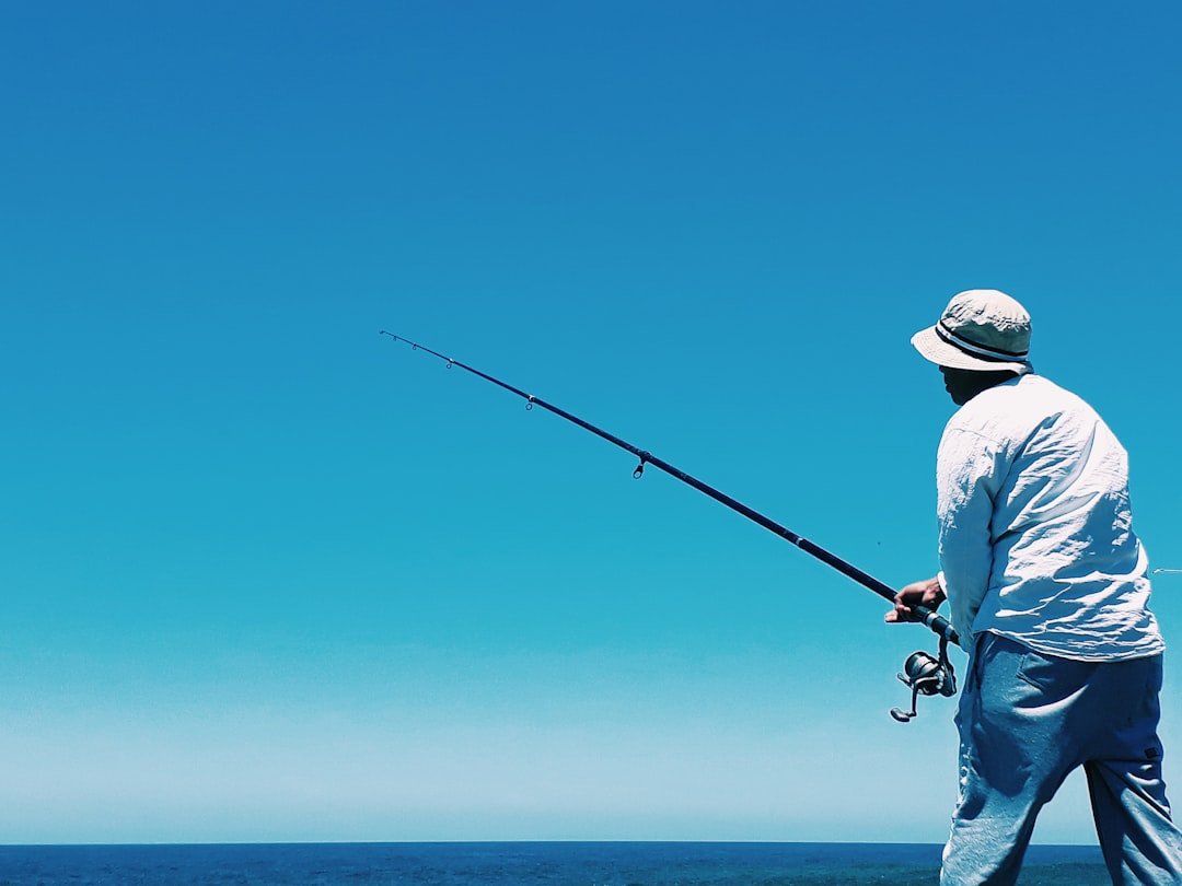 Fishing man-in-white-shirt-and-blue-denim-jeans-holding-black-fishing-rod-jxaoxbqwbai